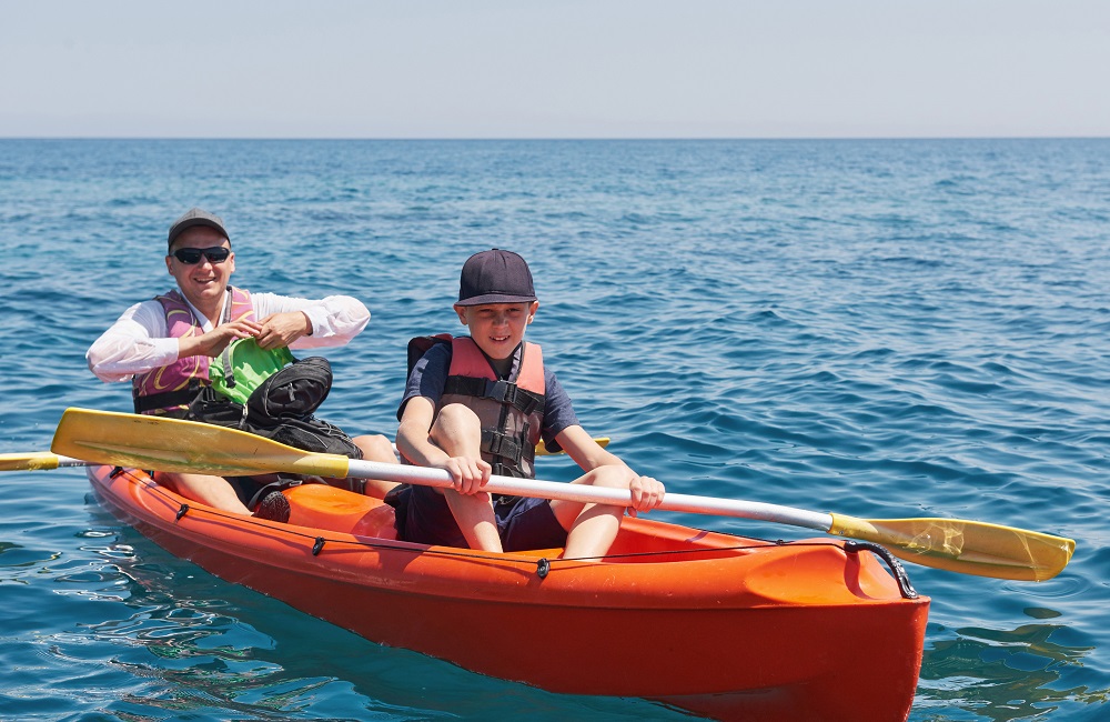 Boat kayaking near cliffs on a sunny day. Kayaking in a quiet bay. Amazing views. Travel, sports concept. Lifestyle. A happy family. RWG